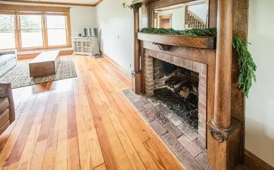a living room with a fireplace and wooden floors at Nature Valley Farm- 2BD/1BA on private 53 acres in North Lawrence