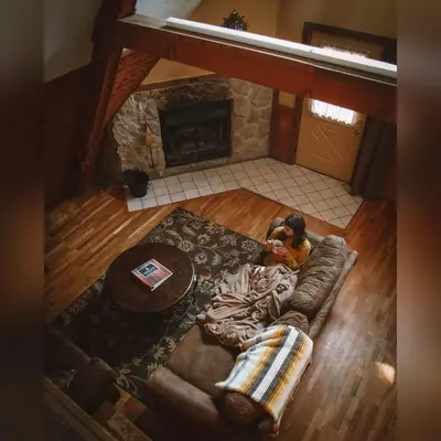 a person laying on a couch in a living room with a fireplace at A-Frame #01 - by The Chalets in Logan