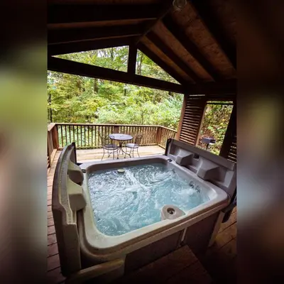 a jacuzzi tub on a deck with a table at A-Frame #03 - by The Chalets in Logan
