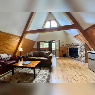 a living room with couches and a stone fireplace at A-Frame #03 - by The Chalets in Logan