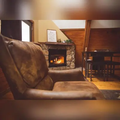 a leather couch in a living room with a fireplace at A-Frame #03 - by The Chalets in Logan