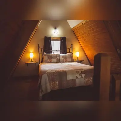 a bedroom with a bed with two lamps and a window at A-Frame #04 - by The Chalets in Logan