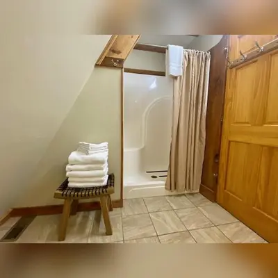 a bathroom with a shower and a pile of towels at A-Frame #04 - by The Chalets in Logan