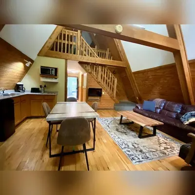 a living room with a table and a couch at A-Frame #05 - by The Chalets in Logan