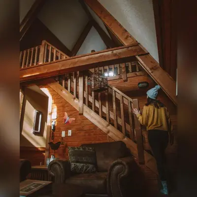 a woman walking up the stairs of a cabin at A-Frame #06 - by The Chalets in Logan
