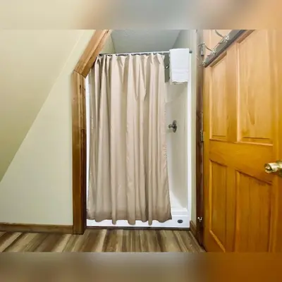 a room with a shower with a curtain and a door at A-Frame #09 - by The Chalets in Logan