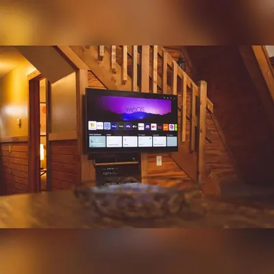 a flat screen tv in a room with a staircase at A-Frame #09 - by The Chalets in Logan