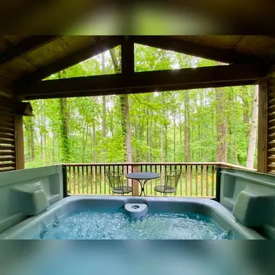 a hot tub on a screened in porch with a table at A-Frame #11 - by The Chalets in Logan