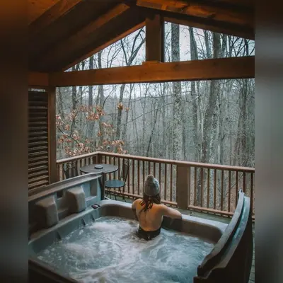 a woman sitting in a hot tub on a porch at A-Frame #11 - by The Chalets in Logan