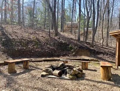a group of logs on the ground next to two benches at A-Frame #12 - by The Chalets in Logan