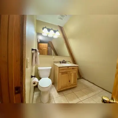 a bathroom with a toilet and a sink and a mirror at A-Frame #12 - by The Chalets in Logan