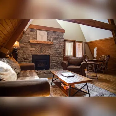 a living room with a stone fireplace and a table at A-Frame #14 - by The Chalets in Logan