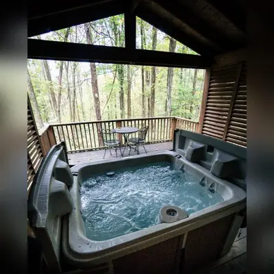 a jacuzzi tub on the deck of a cabin at A-Frame #16 - by The Chalets in Logan