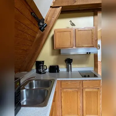 a kitchen with a sink and wooden cabinets at A-Frame #16 - by The Chalets in Logan