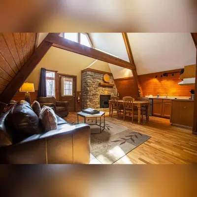 a living room with a couch and a kitchen at A-Frame #15 - by The Chalets in Logan