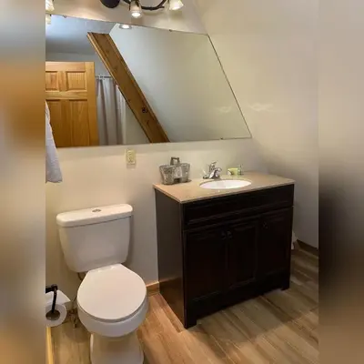 a bathroom with a toilet and a sink with a mirror at A-Frame #17 - by The Chalets in Logan