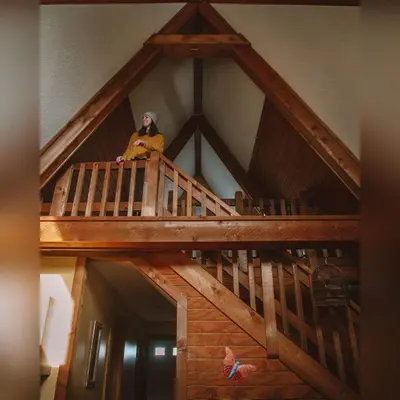 a woman sitting on top of a wooden staircase at A-Frame #17 - by The Chalets in Logan