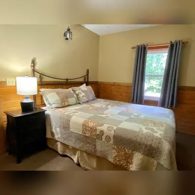 a bedroom with a bed with a lamp and a window at A-Frame #17 - by The Chalets in Logan