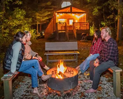 a group of people sitting around a fire at A-Frame #18 - by The Chalets in Logan
