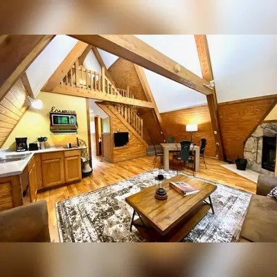 a living room with a table and a kitchen at A-Frame #18 - by The Chalets in Logan