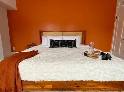 a bedroom with a large bed with an orange wall at Jungle House Columbus Sleep 12 Downtown Ohio Free Parking - Near Convention Center & Nationwide Arena - 4BR Short North Luxury Home - Over 5,800 Five Star Stays in Columbus
