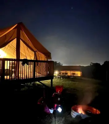 a lit up tent in a field at night at Hocking Hills Deluxe Safari Glamping Tents in Logan