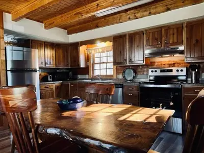 a kitchen with a wooden table and a kitchen with a stove at Alpine - by The Chalets in Logan