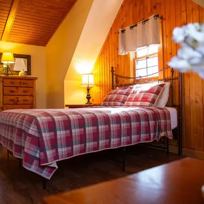 a bedroom with a bed with a plaid blanket and a window at Alpine - by The Chalets in Logan