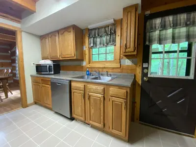 a kitchen with wooden cabinets and a sink and a black door at Aspen - by The Chalets in Logan
