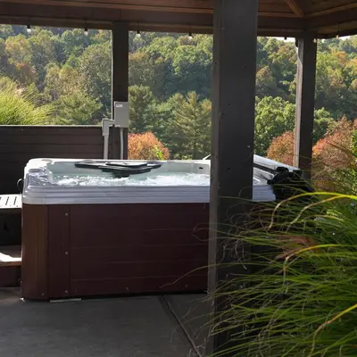 a hot tub on a patio with a view of trees at Big Sky Lodge - by The Chalets in Logan