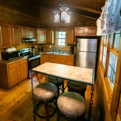 a kitchen with a table and chairs and a refrigerator at Blackjack - by The Chalets in Logan