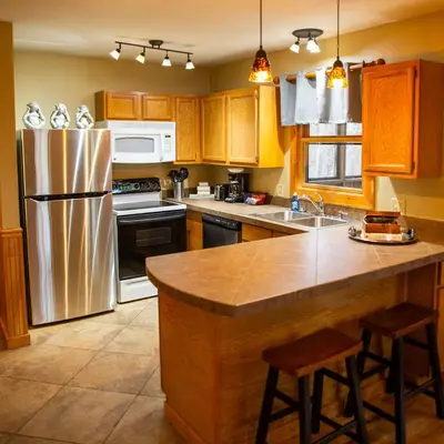 a kitchen with wooden cabinets and a stainless steel refrigerator at Couples Paradise II - by The Chalets in Logan