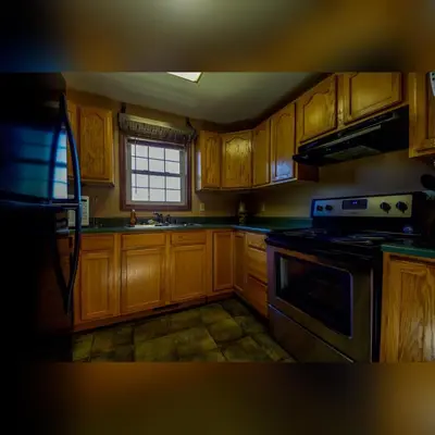 a kitchen with wooden cabinets and a stove top oven at Coyote - by The Chalets in Logan