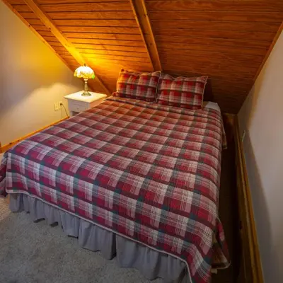 a bed with a plaid blanket and pillows in a room at Cumberland - by The Chalets in Logan