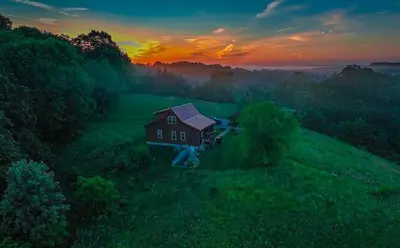 a house in the middle of a field at sunset at Deer Run - by The Chalets in Logan