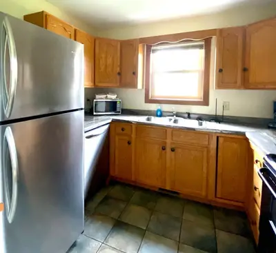 a kitchen with wooden cabinets and a stainless steel refrigerator at Deer Run - by The Chalets in Logan
