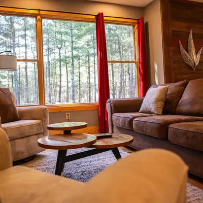 a living room with two couches and a table and a window at Evergreen - by The Chalets in Laurelville