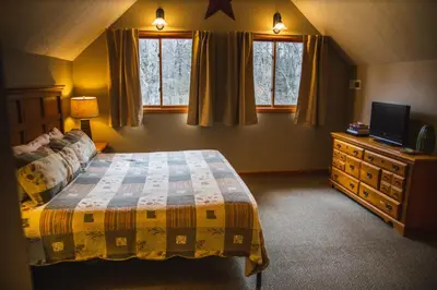a bedroom with a bed and a tv and windows at Fireside Lodge - by The Chalets in Logan
