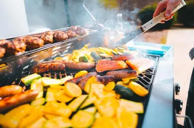 a person grilling meat and vegetables on a grill at Grande Butte Lodge - by The Chalets in Laurelville