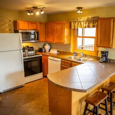 a kitchen with wooden cabinets and a white refrigerator at Hawks Peak - by The Chalets in Logan
