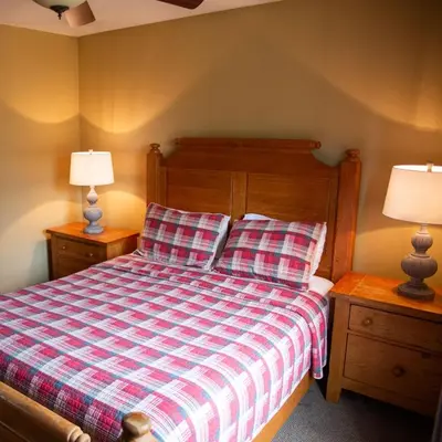 a bedroom with a bed with a plaid blanket and two lamps at Hawks Peak - by The Chalets in Logan