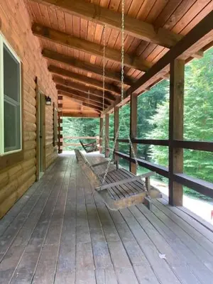 a porch of a log cabin with a swing at Hidden Heights - by The Chalets in South Bloomingville
