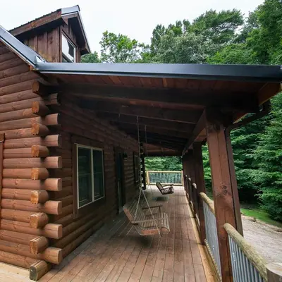 a porch of a log cabin with a porch swing at Hidden Heights - by The Chalets in South Bloomingville