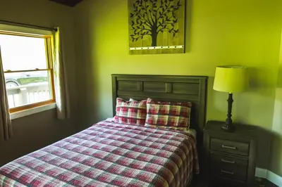 a bedroom with a bed and a lamp and a window at Lakeview - by The Chalets in Logan