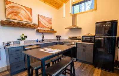 a kitchen with a table and a black refrigerator at Legends Lane A - by The Chalets in Logan