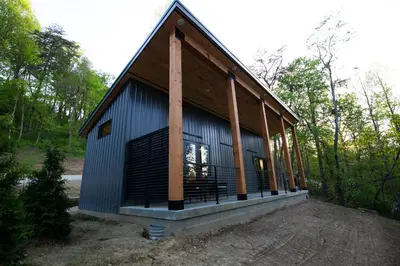 a small house with a gambrel roof in the woods at Legends Lane B - by The Chalets in Logan