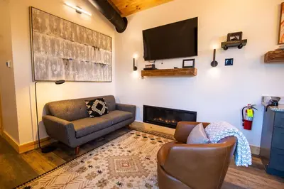 a living room with a couch and a tv on a wall at Legends Lane D - by The Chalets in Logan