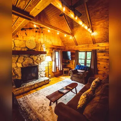 a living room with a stone fireplace in a log cabin at Oakridge - by The Chalets in South Bloomingville