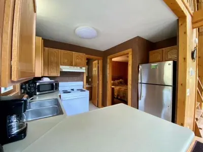 a kitchen with a stainless steel refrigerator and wooden cabinets at Pine Cone - by The Chalets in Logan