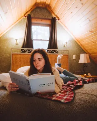 a woman laying on the floor reading a book at Pine Cone - by The Chalets in Logan